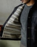 [おすすめアイテム] T.T デニムジャケット ブランケットライニング仕様 C.1920'S / LOT.703 カラー：ロウインディゴ サイズ：40、42 LOT.703デニムジャケットは、LOT.704デニムトラウザーズと並ぶ定番モデルです。ブランドを代表するアイコニックな一着ですが、今シーズンはライニングにオリジナルブランケットを採用した秋冬仕様が登場。ブラウン・グレー・ベージュのボーダー柄ブランケットは、縦糸にコットン、緯糸に英国羊毛をブレンドしたメランジウールで織り上げ、起毛とワッシャー加工で仕上げています。程よい粗野感のあるツイードのような風合いが魅力。特注の鉄製刻印入りボタン、バックパーツ、泥染めレザーパッチも健在です。ブランケットの厚み分タイトな着用感のため、ニットなどをインナーに合わせる場合はワンサイズ上をおすすめします。サイズ42着用（176cm／70kg）【お問い合わせ】 Fashionformstudio TEL: 03-5772-9622 e-mail: info@fashionformstudio.com